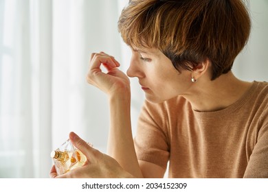 Caucasian Middle Aged Woman Inhaling Aroma Of Perfume Bottle. Loss Of Smell Due To Coronavirus Pandemic. Concept Of Long-term Effect Of Covid19. Self-checking For Infection And Receptor Blindness