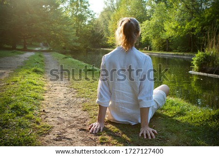 Caucasian middle aged woman  wearing white linen sitting next to a river in the sunshine, back view. Stock photo © 