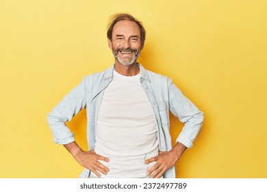 Caucasian middle-aged man in yellow studio confident keeping hands on hips. - Powered by Shutterstock