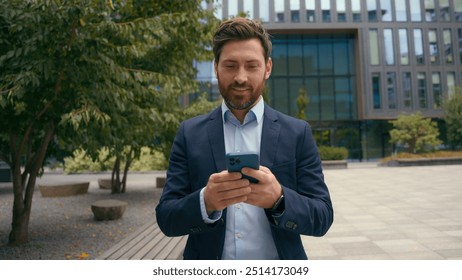 Caucasian middle-aged positive businessman in city male entrepreneur employer man business browsing chatting smartphone web distant communication connection looking away message with mobile phone - Powered by Shutterstock