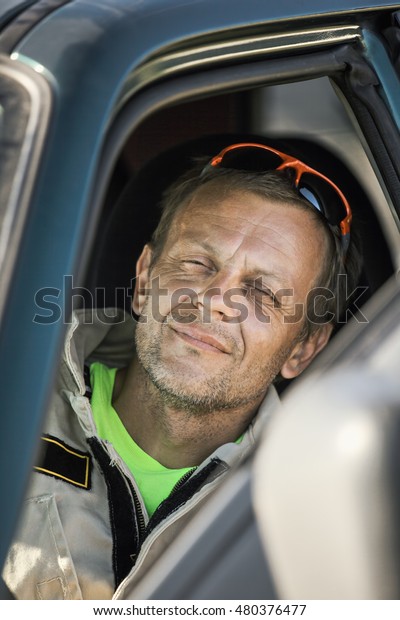 Caucasian\
middle-aged rescuer on duty sitting in a\
car