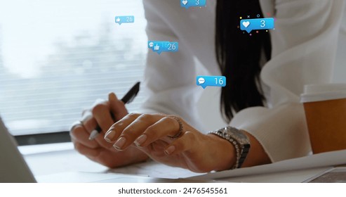 A Caucasian middle-aged woman wearing white blouse is writing. She has a wedding ring, polished nails, and a coffee cup nearby - Powered by Shutterstock