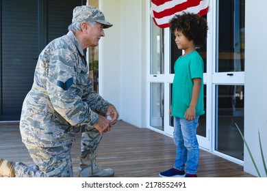 Caucasian Military Grandfather In Camouflage Clothing Looking At Biracial Grandson Outside House. Unaltered, Family, Togetherness, Childhood, Military, Patriotism And Homecoming.