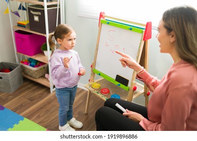 Caucasian Mom Asking A Question To Her Little Daughter For A Grammar Class. Beautiful Homeschool Girl Listening To Her Female Teacher 