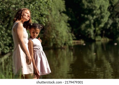 Caucasian Mother And African-American Daughter Admire Nature On A Lake On A Summer Day,side View.Summer,family,diverse People.Selective Focus,copy Space.