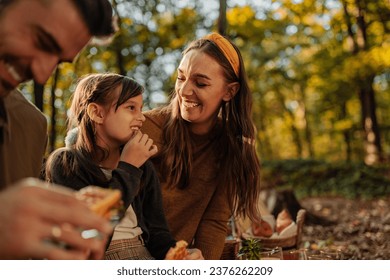 Caucasian mother, father and daughter are on a picnic in a forest during fall, eating waffles and fruit - Powered by Shutterstock