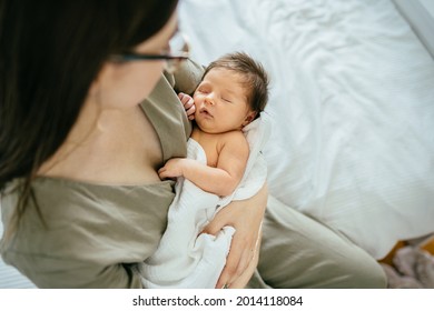 Die kaukasische Mutter in Brille stürzt das Kind. Porträt des schlafenden Neugeborenen in den Armen der Mutter. Sorgfältig Liebe Empfindlichkeit. Baby gesund schlafen. Kleinkindersüße kleine Tochter. Wirklicher Augenblick des Lebens.