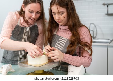 Caucasian Mother Help Little Girl To Decorating Homemade Cake. Daughter Learning Baking Bakery Skill In The Kitchen. Family Support Kid Hobby