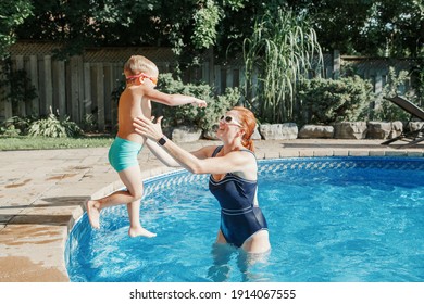 Caucasian Mother Training Toddler Son To Swim In Swimming Pool Outdoor. Baby Boy Diving Jumping In Water With Goggles. Water Family Seasonal Activity Outdoor. Healthy Active Lifestyle. 