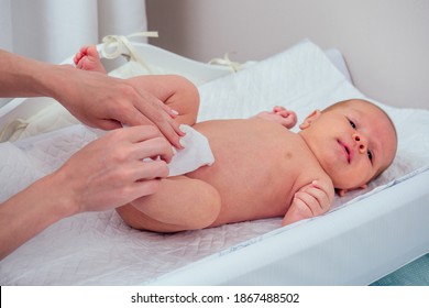 Caucasian Mother Using Wet Wipes,applying Baby Powder Before Putting Diapers On Her Four Month Old Baby In Bed At Home