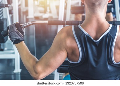 Caucasian muscular man using pull down machine in the gym, weight lifting workout. - Powered by Shutterstock