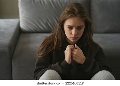 Caucasian nervous woman sitting at the couch in home