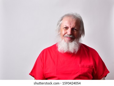 Caucasian Old Man With A Long Beard And Red Shirt Giving A Sarcastic Smile.