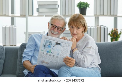 Caucasian old senior elderly grandparent grey bearded hair husband and pretty wife sitting cuddling together on cozy sofa in living room at home in morning reading funny news on daily newspaper. - Powered by Shutterstock