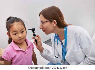 Caucasian Pediatrician Examining Japanese Girl With Otoscope, Hearing Check-up For Child. Hearing Exam