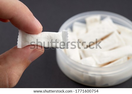 caucasian person holds tobacco pouch over black background. copy space. alternative chewing nicotine smoking.