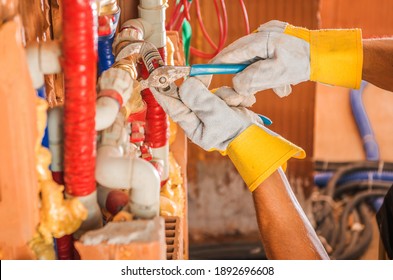 Caucasian Plumber Finishing Whole New Water Supply System Inside Concrete Blocks Build Commercial Building. Close Up On His Hands.