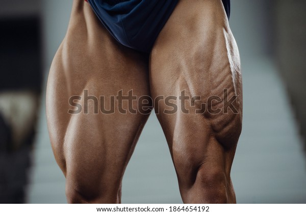 Caucasian power athletic man training pumping up\
leg quadriceps muscles. Strong bodybuilder with six pack, perfect\
abs, triceps, chest, shoulders in gym. Fitness and bodybuilding\
concept