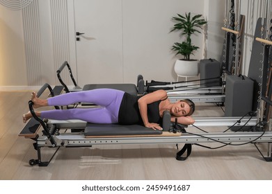 Caucasian pregnant woman doing Pilates exercises on a reformer machine.  - Powered by Shutterstock