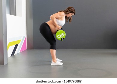 Caucasian Pregnant Woman In Her Third Trimester Doing Weight Lifting Exercises With A Heavy Bag In A Gym Wearing Sports Or Fitness Clothing