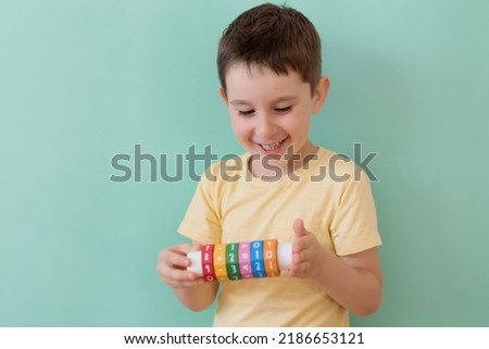 Caucasian preschool boy with arithmetic math learning toy on a light green background with copy space