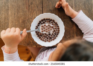 Caucasian preschool girl eating chocolate cereals with milk before school. Lifestyle morning breakfast top view - Powered by Shutterstock