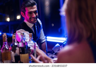 Caucasian profession bartender making a cocktail for women at a bar. Attractive barman pouring mixes liquor ingredients cocktail drink from cocktail shaker into the glass at night club restaurant. - Powered by Shutterstock