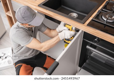 Caucasian Professional Cabinetmaker in His 40s Assembling Kitchen Cabinets Furniture - Powered by Shutterstock