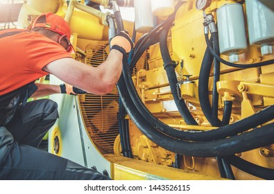 Caucasian Professional Mechanic Fixing Bulldozer Engine Inside Heavy Equipment Repair Shop.