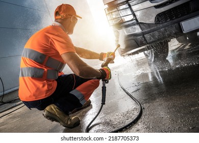 Caucasian Professional Truck Driver Pressure Washing A Vehicle. Powerful Commercial Truck Washer.