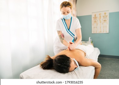 Caucasian Professional Woman Giving A Physiotherapeutic Back Massage Wearing A Face Mask Due To The Covid 19 Coronavirus Pandemic