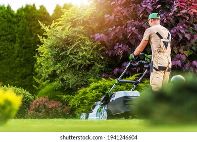 Caucasian Residential Garden Worker in His 40s Trimming Backyard Lawn Using Electric Cordless Grass Mower. Landscaping and Gardening Industry Theme. - Shutterstock ID 1941246604