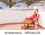 Caucasian resting woman is sitting and dreaming in a chair at the terrace with view on the sea. Relaxing beautiful young female model.  Image has copyspace for text. Outdoor (Sharm El Sheikh, Egypt).