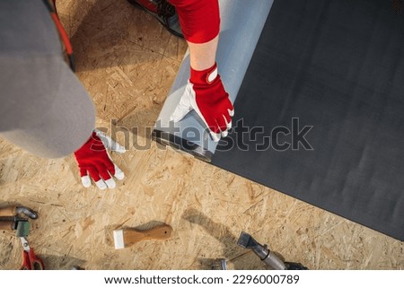 Caucasian Roofing Worker Installing EPDM Rubber Membrane on Top of Plywood Roof