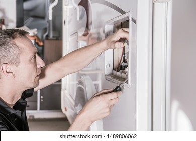 Caucasian RV Repair Technician In His 40s Looking For Potential Problem Inside Travel Trailer Propane Gas Heating System Compartment.