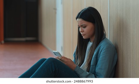 Caucasian sad upset student girl female schoolgirl woman ill reading bad news thinking pupil teen in school university college sitting on floor education study problem using mobile phone smartphone - Powered by Shutterstock