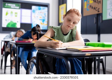 Caucasian schoolgirl in wheelchair with diverse schoolchildren in school classroom. Education, inclusivity, school, learning and disability concept. - Powered by Shutterstock