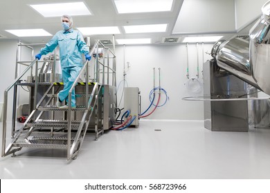 caucasian scientist in blue lab suit and gloves stand on steel ladder and check readings  - Shutterstock ID 568723966