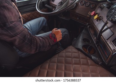 Caucasian Semi Truck Driver Behind The Steering Wheel. Manual Transmission In Aged Vintage Truck. Transportation Industry.