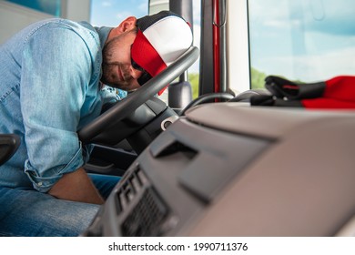 Caucasian Semi Truck Driver in His 30s Wearing Baseball Hat Sleeping on the Steering Wheel While on the Truck Stop. Long Haul Theme.