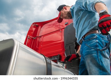 Caucasian Semi Truck Driver In His 30s Looking At Diesel Tank Cap Looking For Leaks Or Stolen Diesel Fuel. Transportation Industry Theme.