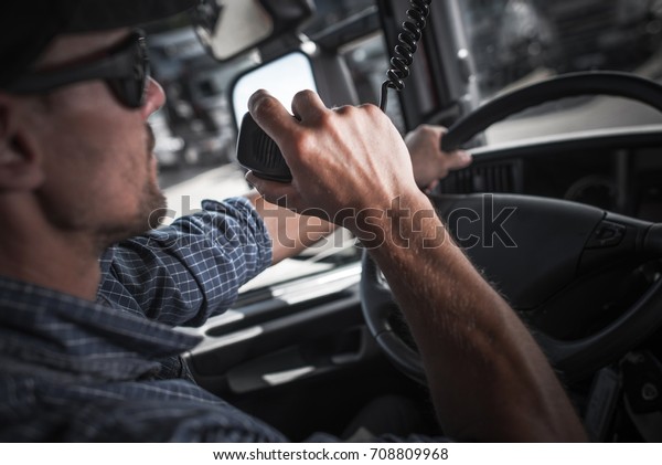 Caucasian Semi Truck Driver Talking on the CB\
Radio with Other Truckers in a\
Convoy.