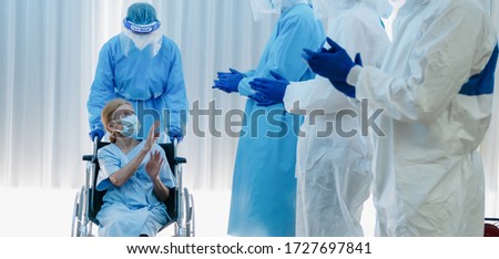 caucasian senior coronavirus covid-19 infected patient sitting on wheel chair with happy doctor and medical team ready to send her back home after treatment and recover from desease at hospital