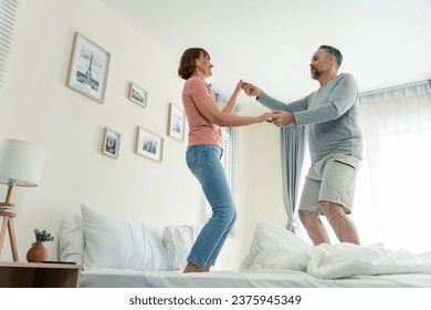 Caucasian senior couple dancing with music together in bedroom at home. Elderly older grandfather and grandmother smiling, feeling in love and enjoy relationship and activity in house after retirement - Powered by Shutterstock