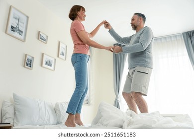 Caucasian senior couple dancing with music together in bedroom at home. Elderly older grandfather and grandmother smiling, feeling in love and enjoy relationship and activity in house after retirement - Powered by Shutterstock