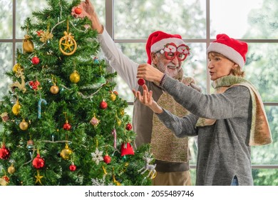 caucasian senior couple with sweater and santa hat feel happy decorate Christmas tree together in Christmas and new year festival celebration at home. Christmas and new year celebration activity