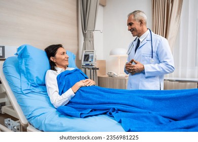 Caucasian senior doctor checking up female patient in hospital ward. Attractive professional practitioner medic man working by giving medical examination to the sick person on bed in recovery room. - Powered by Shutterstock