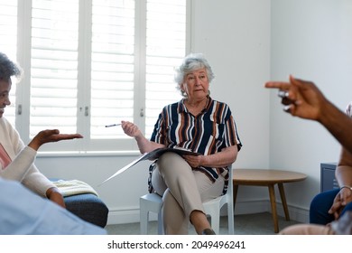 Caucasian Senior Female Counsellor In Face Mask Advising Diverse Group Of Senior Friends. Senior Health, Support And Lifestyle.