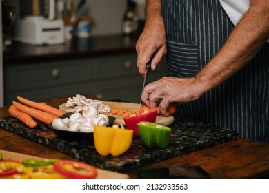 Caucasian Senior Male Chopping Vegetables In Kitchen