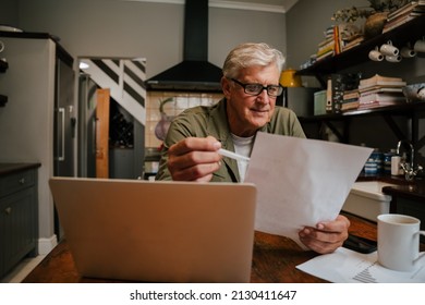 Caucasian Senior Male Working And Reading Reports